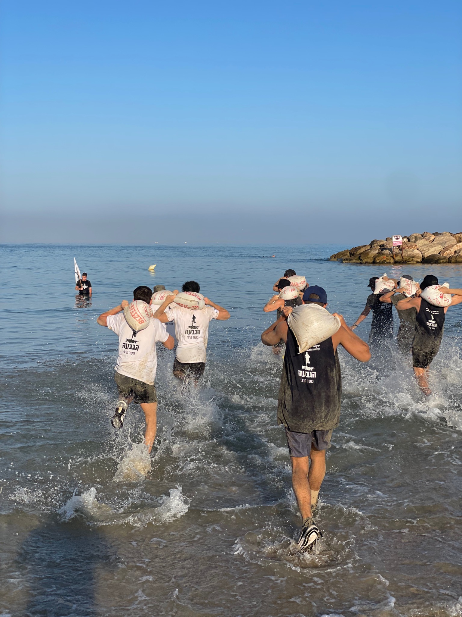 אימון קבוצתי עם שקי חול בים
